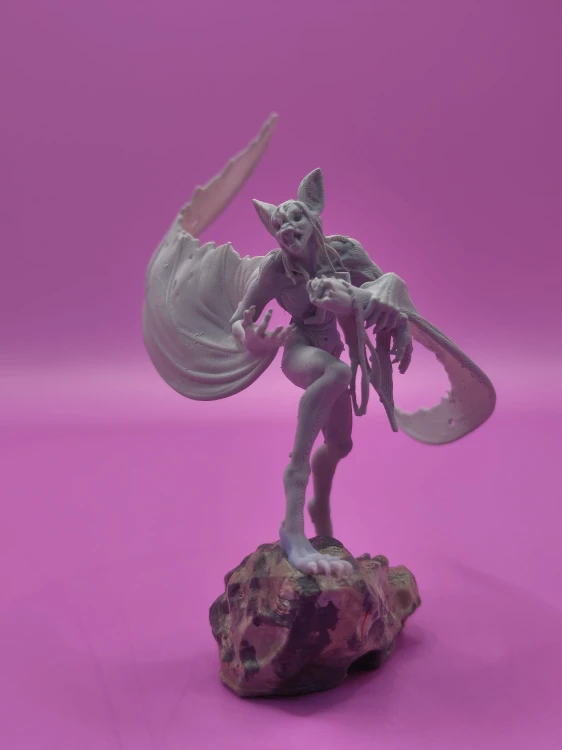 Figurka humanoidalnej kreatury z rozpostartymi skrzydłami nietoperza, wydrukowana w 3D w odcieniu szarości. Dynamiczna poza, wysoka jakość detali. Idealna do RPG, horroru, dioram i kolekcji.
